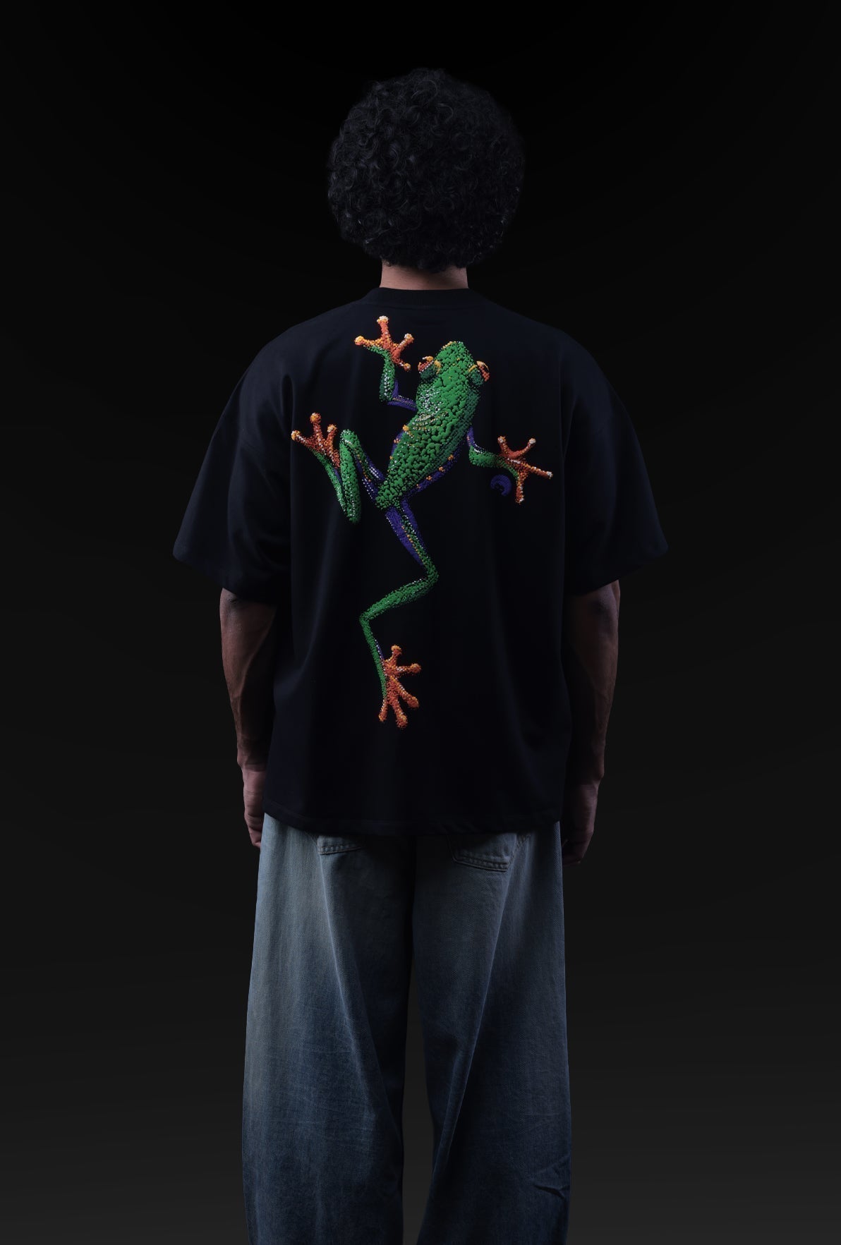 Person wearing a black t-shirt with a colorful frog design on the back against a dark background Crepdog Crew