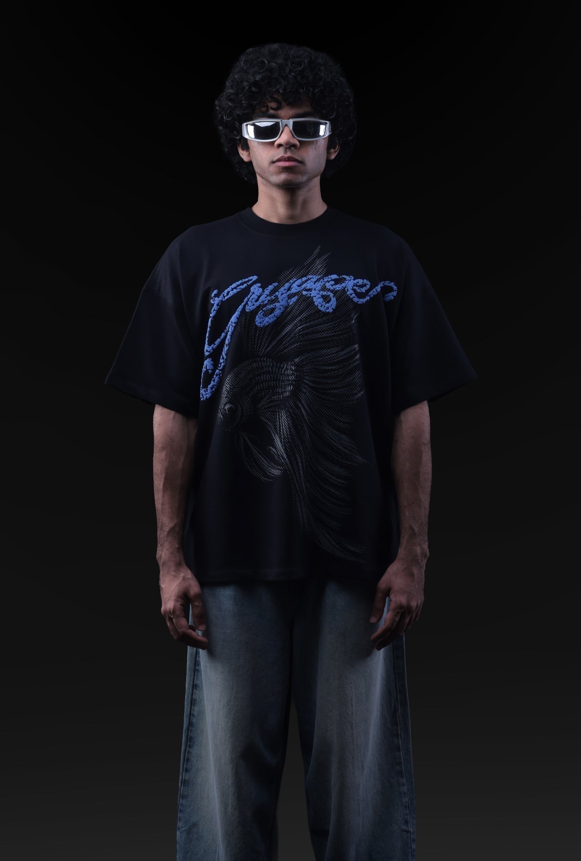 Person wearing a black t-shirt with blue text and sunglasses against a dark background Crepdog Crew