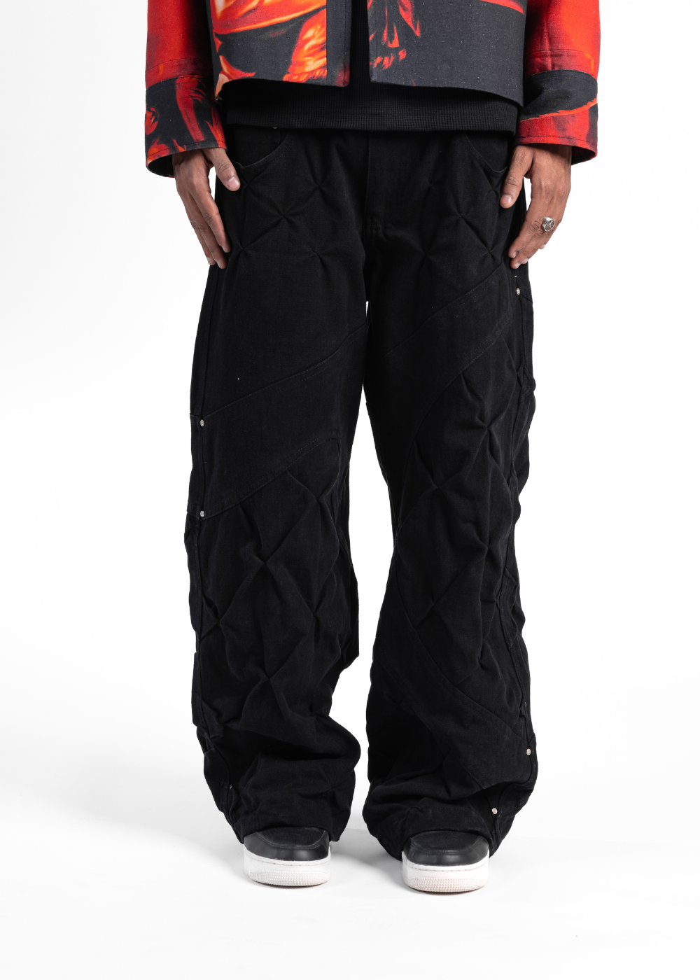 Person wearing black snow pants with a colorful jacket on a white background