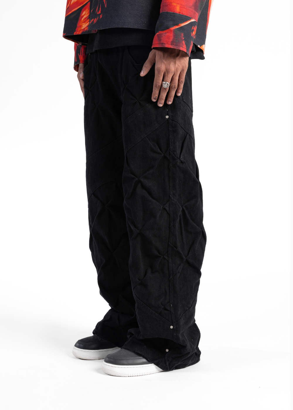 Person wearing black quilted pants with a colorful jacket on a white background