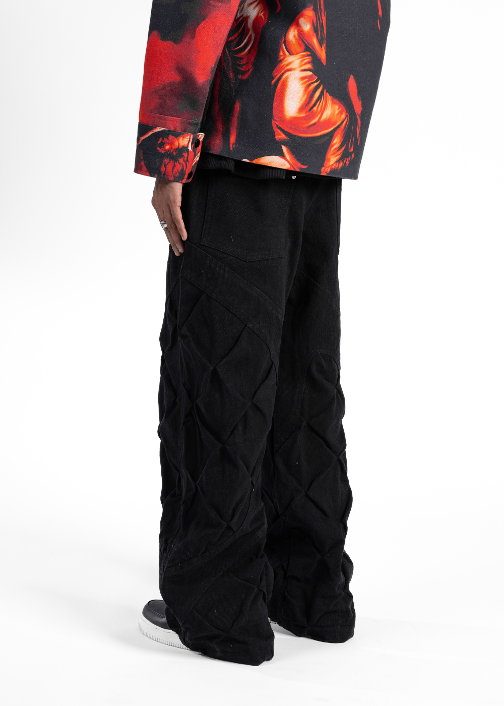 Person wearing black cargo pants with a colorful jacket on a white background
