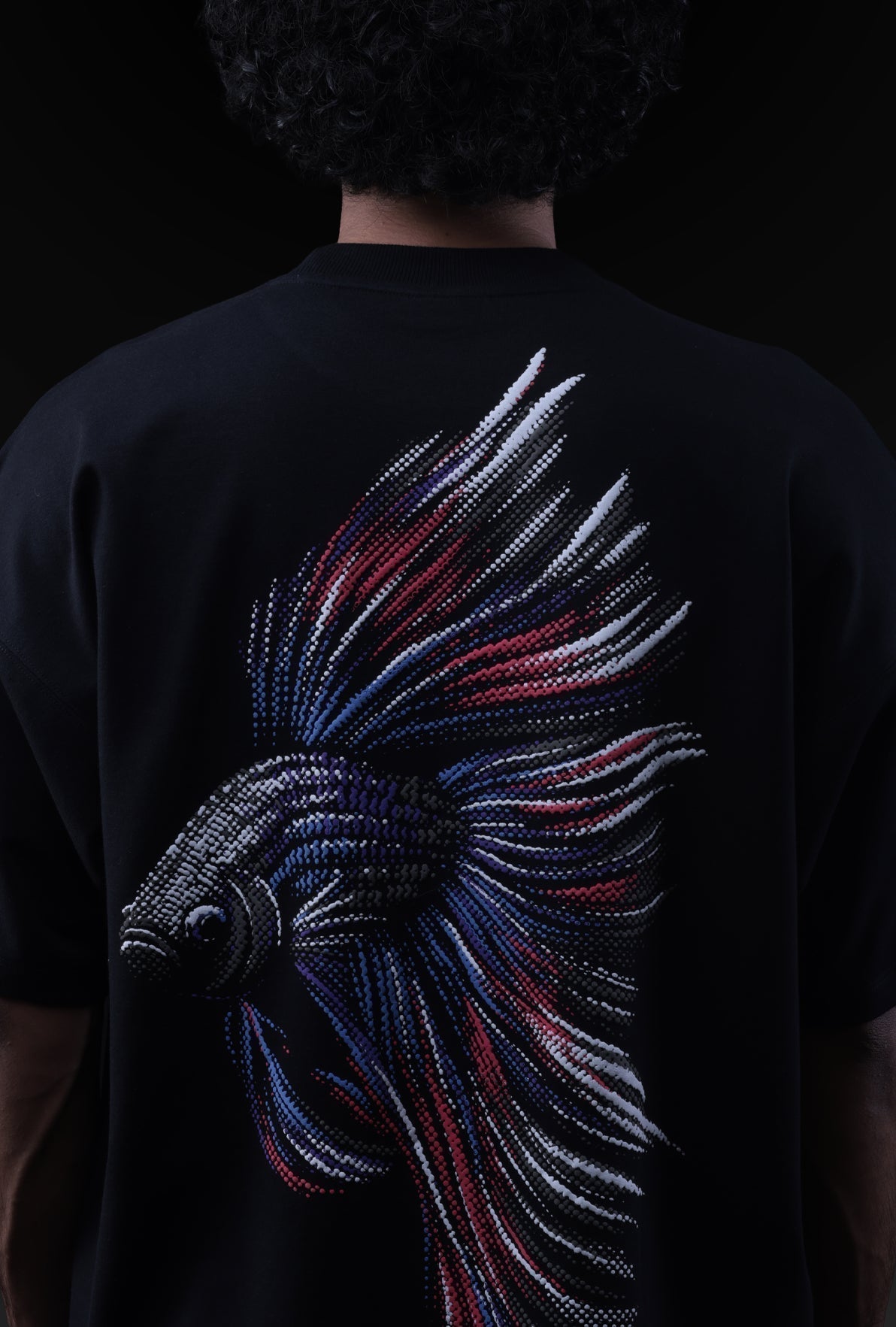 Black t-shirt with a colorful fish design on the back against a dark background
