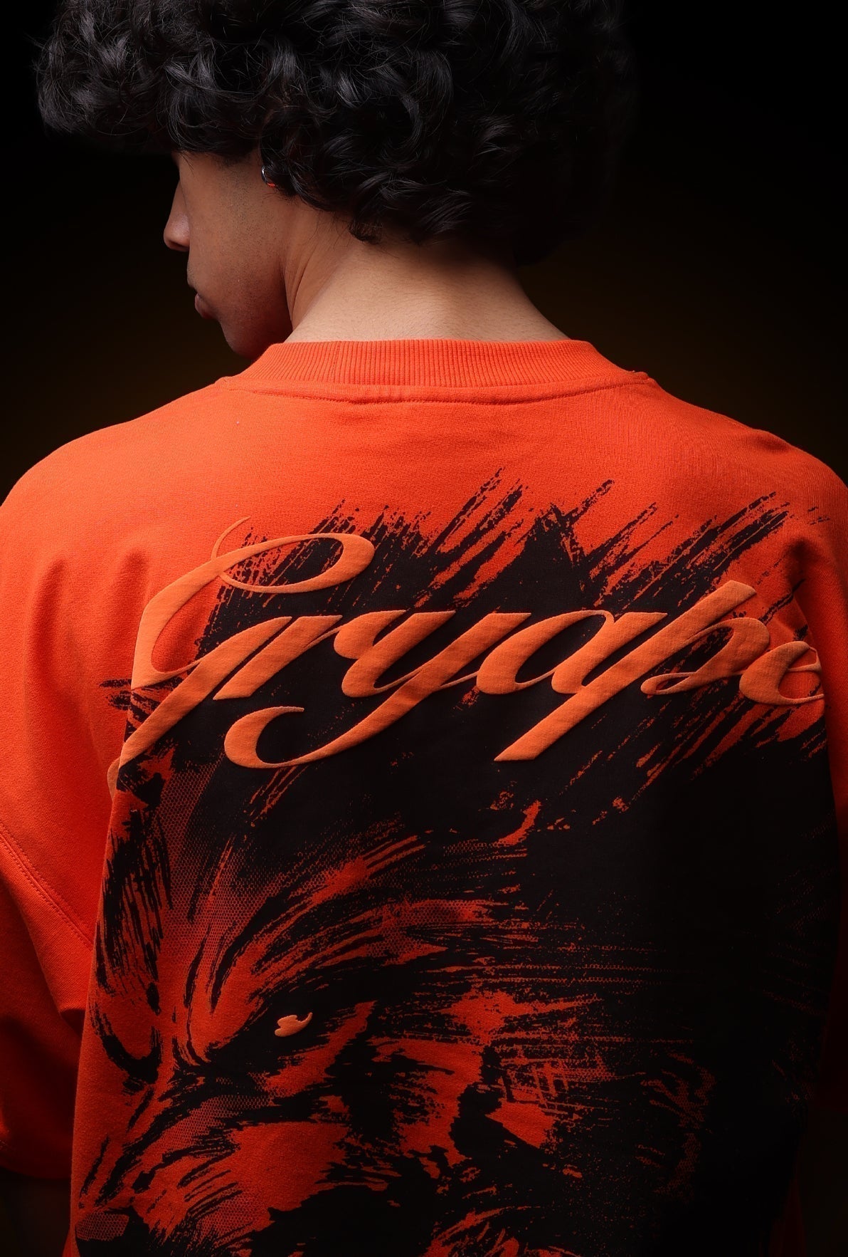Person wearing an orange sweatshirt with black graphics and text on a dark background - Crepdog Crew