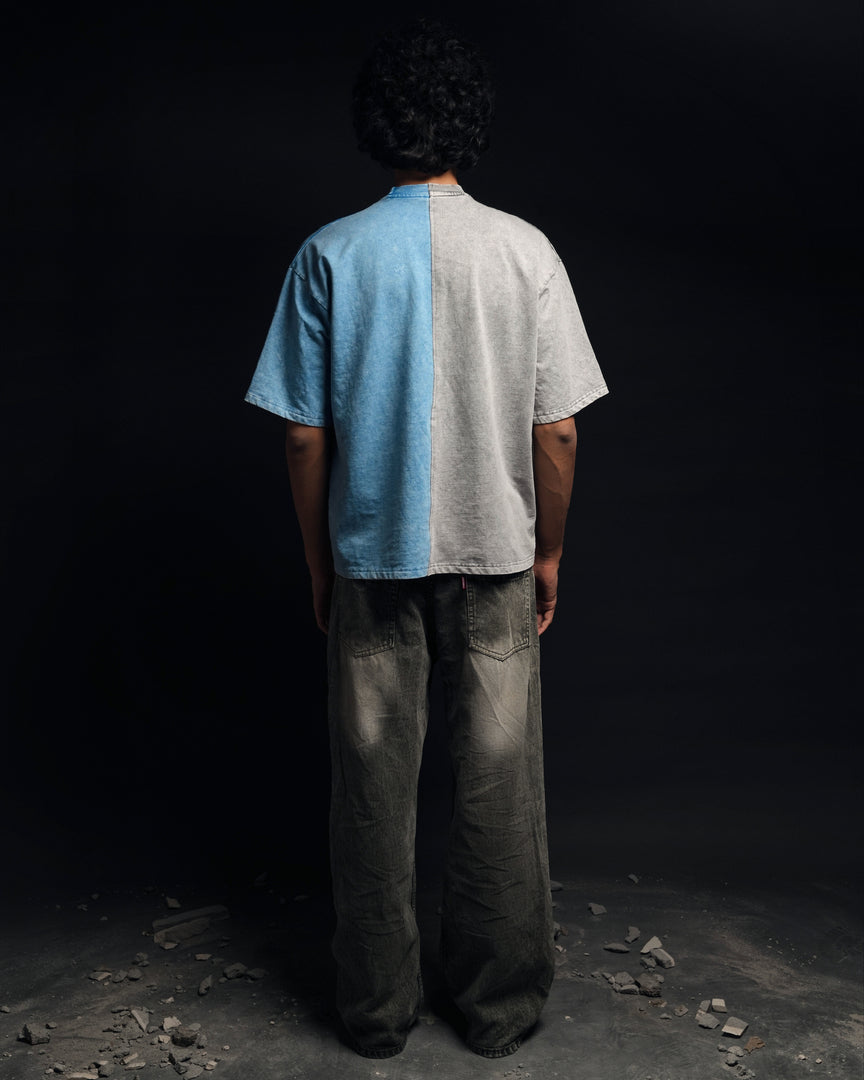 Person wearing a two-tone shirt with blue on one side and gray on the other, standing against a dark background - Crepdog Crew