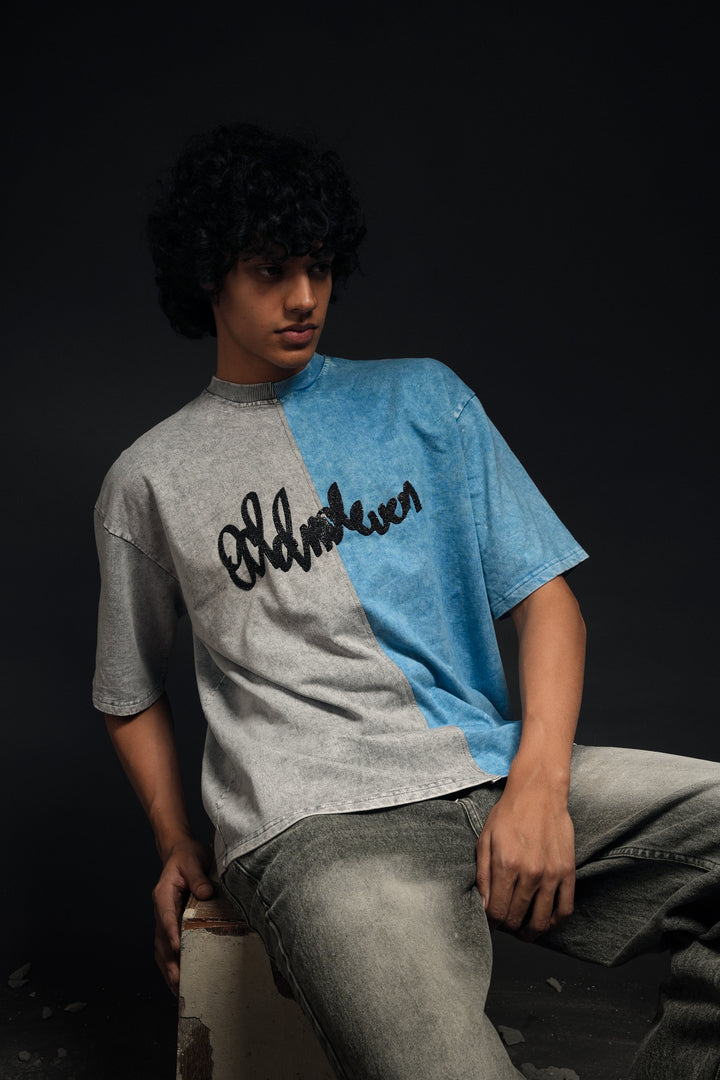 Person wearing a gray and blue shirt with text, sitting against a dark background - Crepdog Crew