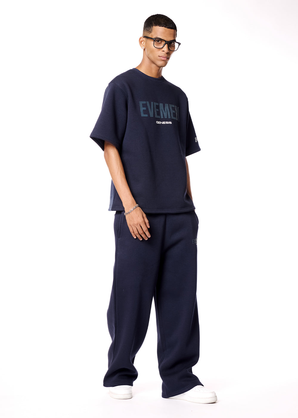 Person wearing a navy oversized t-shirt and pants with 'Everlane' branding on a white background