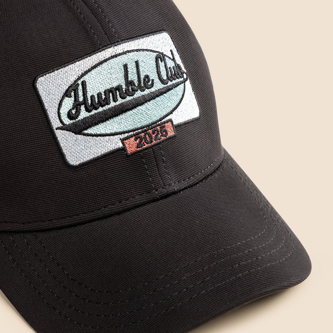 Black cap with 'Humble Club' logo on a beige background