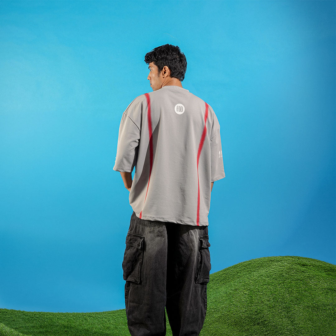 Person wearing a gray shirt with red accents and dark pants standing on grass with a blue sky background Crepdog Crew