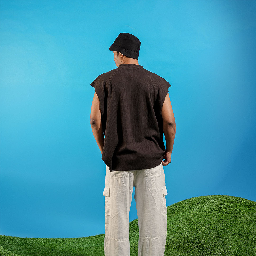 Person wearing a sleeveless brown shirt and light-colored pants standing on grass with a blue sky background Crepdog Crew