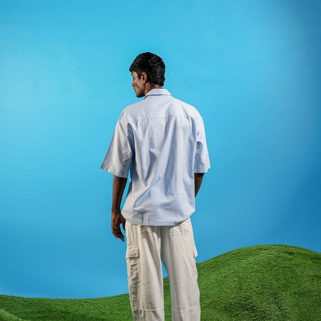 Man in light shirt and pants standing on a grassy hill with a clear blue sky Crepdog Crew