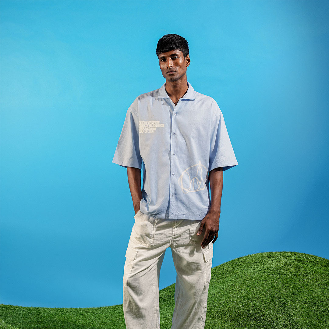 Man wearing a light blue shirt and beige pants standing on a grassy area with a clear blue sky Crepdog Crew