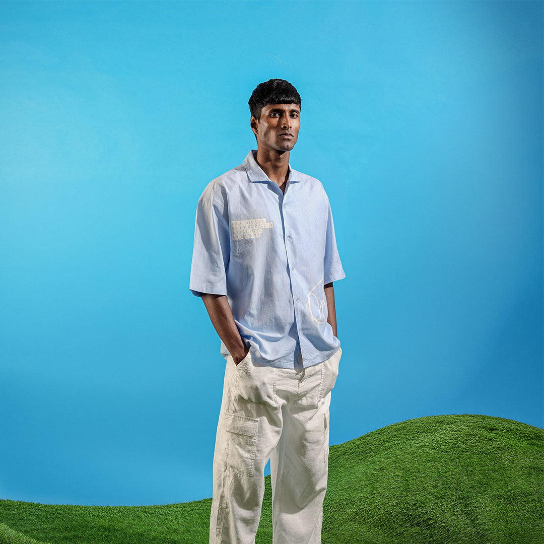 Man in light blue shirt and white pants standing on a green hill with a clear blue sky Crepdog Crew