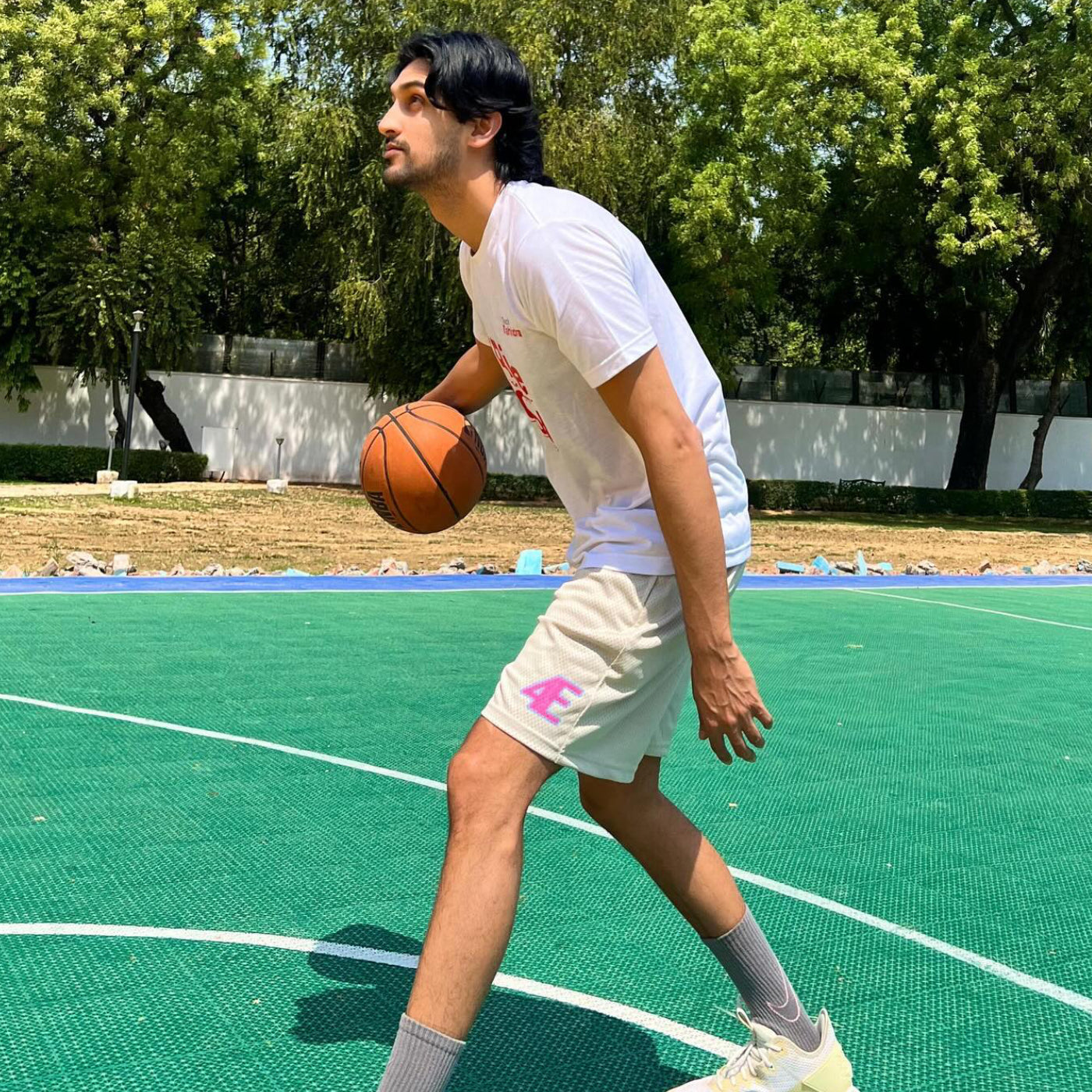 Person playing basketball on an outdoor court with trees in the - Crepdog Crewbackground