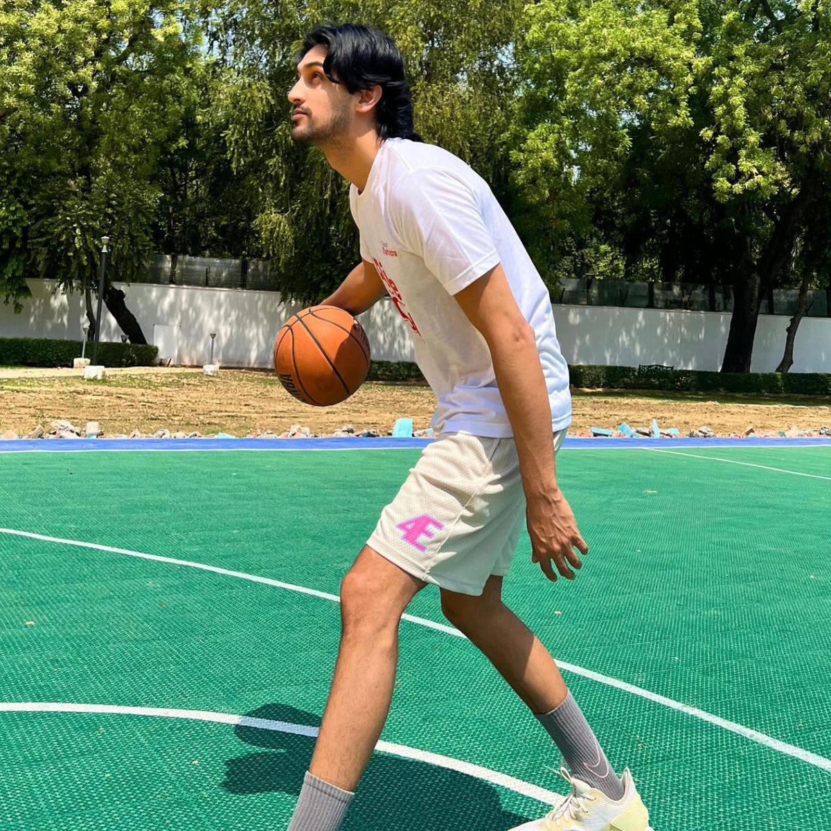 Person playing basketball on an outdoor court with trees in the - Crepdog Crewbackground