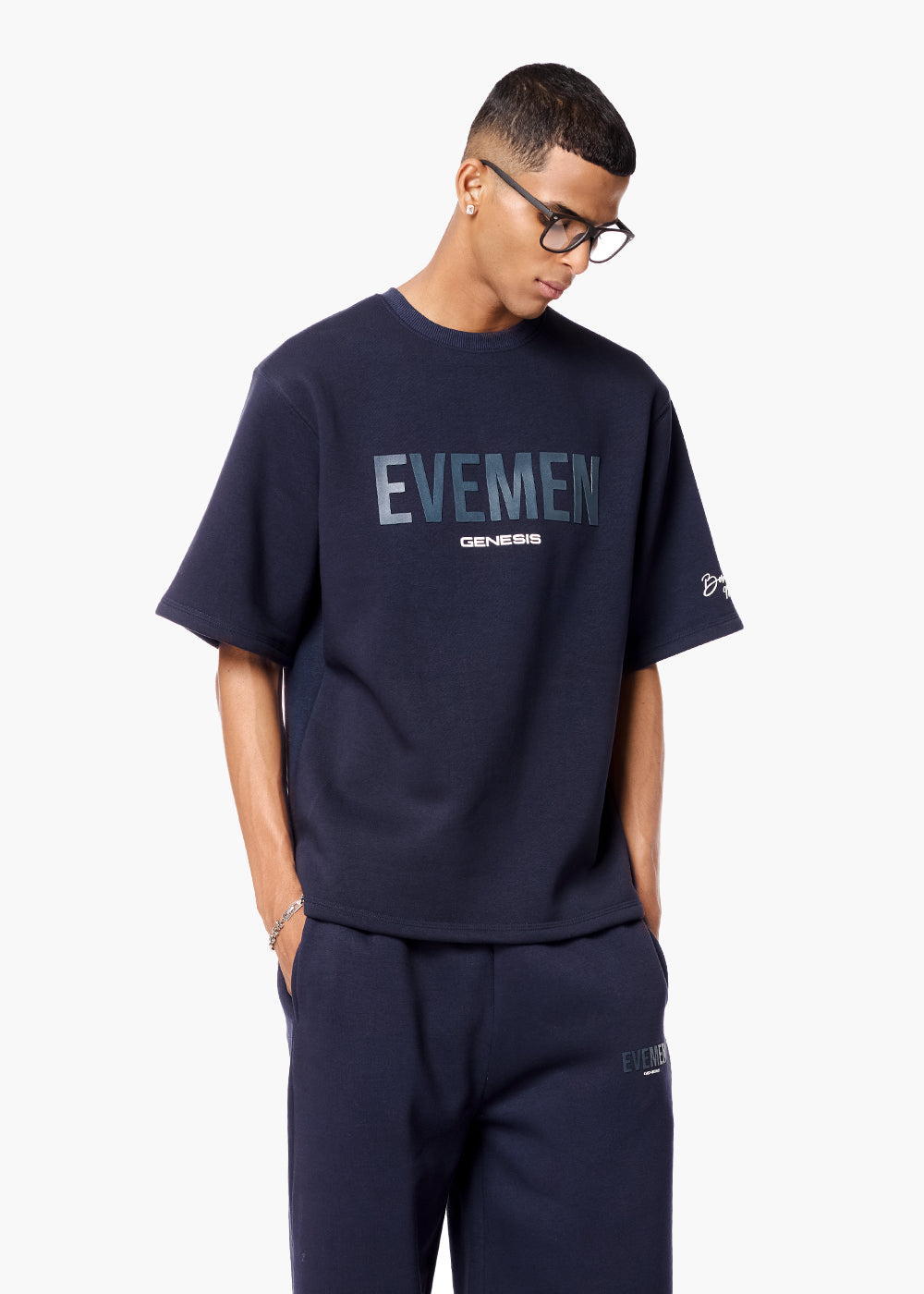 Person wearing a navy blue 'EVMEN' t-shirt and pants on a white background