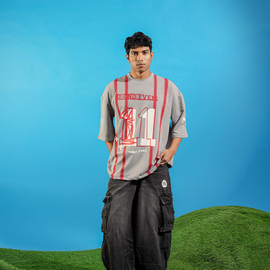 Person wearing a gray t-shirt with red and white design on a blue and green background Crepdog Crew