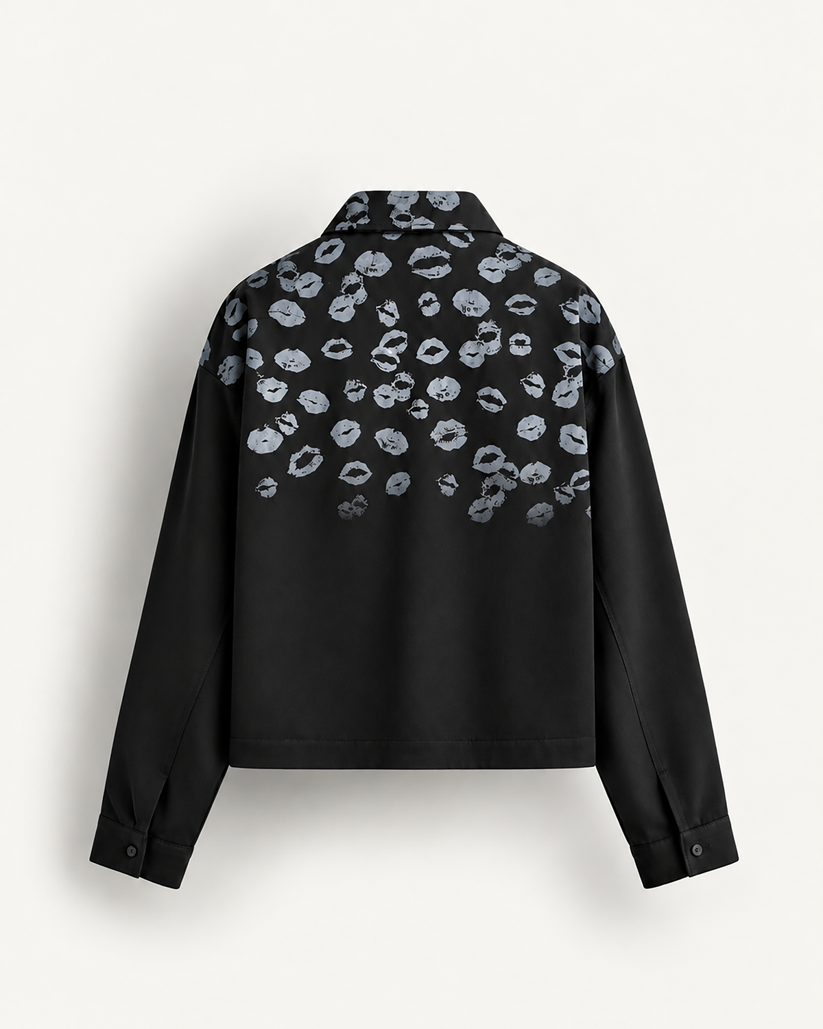 A black cropped button-up shirt jacket featuring a repeating pattern of silver-gray metallic kiss marks across the upper back and shoulders, displayed on a clean off-white background.